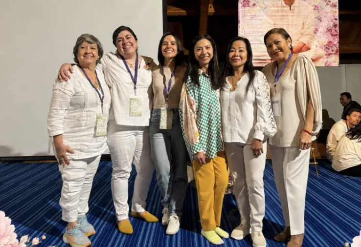 Six women from the program standing arm in arm at an event